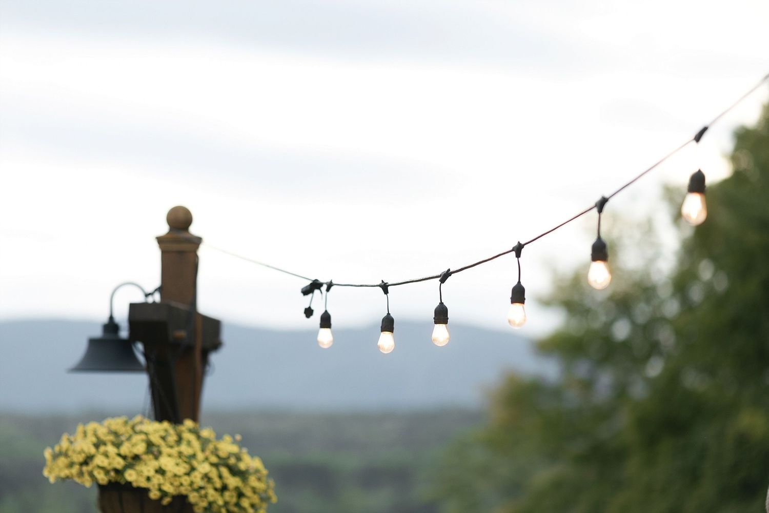 String lights hang against a mountain backdrop creating a romantic outdoor ambiance.