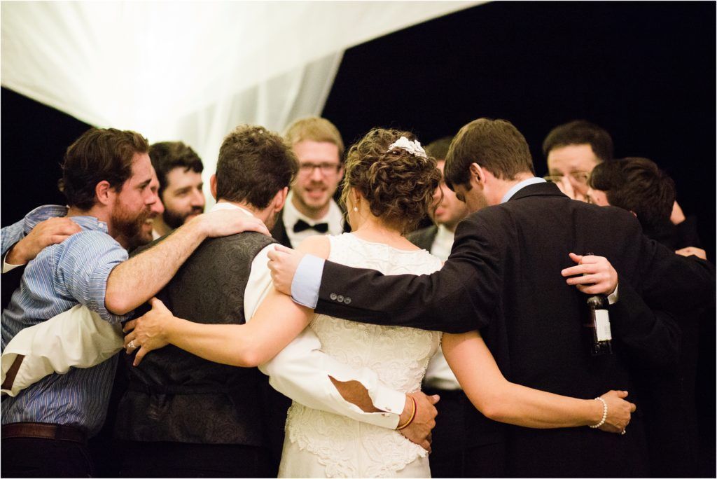 Group huddle of wedding party members sharing an emotional moment.