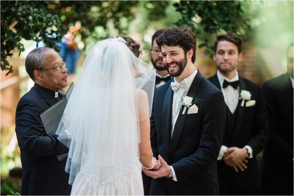 Outdoor wedding ceremony under trees with formal attire.