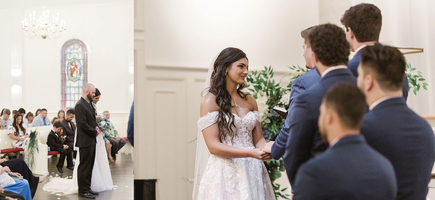 Wedding ceremony in progress inside bright white chapel with decorative floral arrangements.