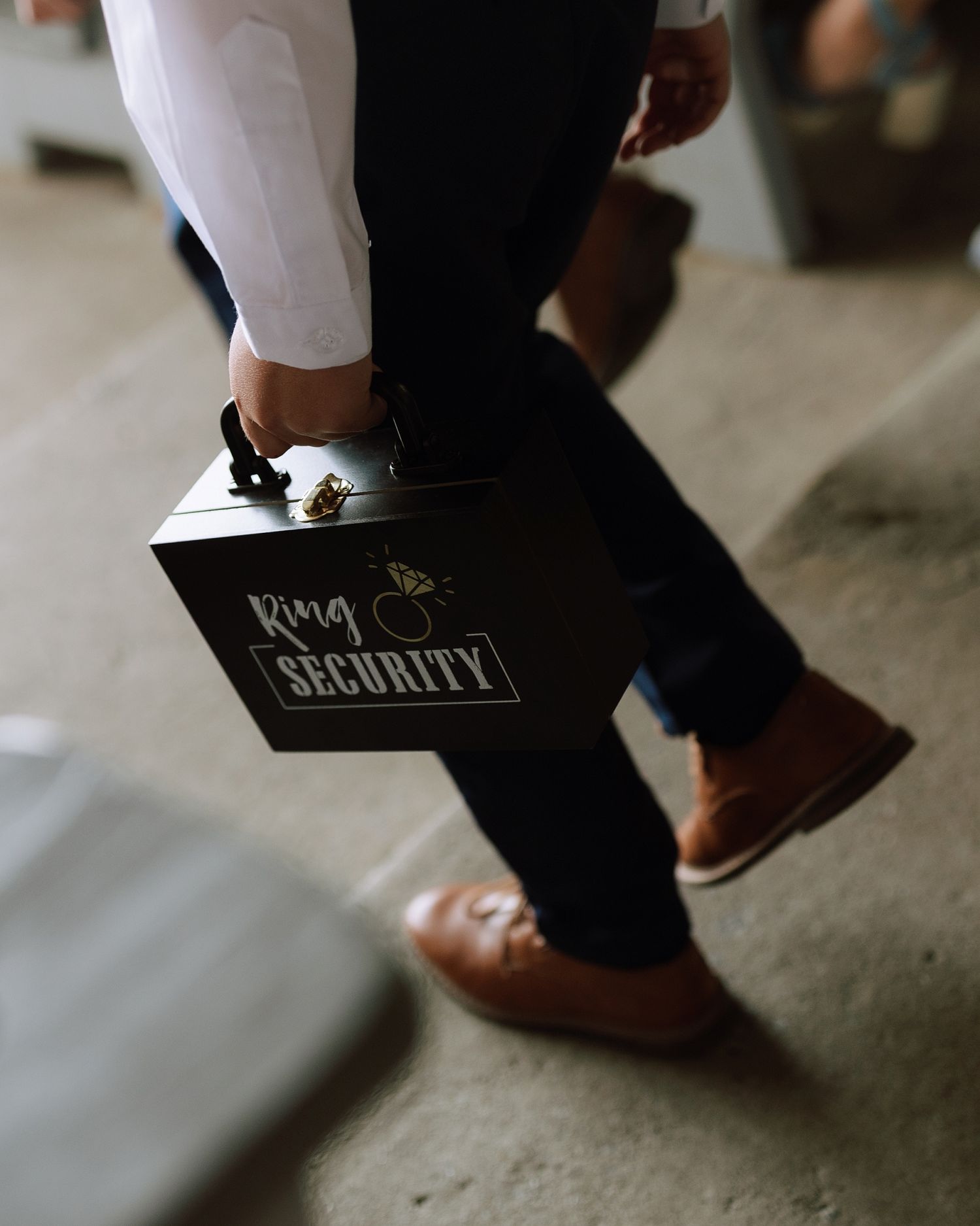 A ring bearer carries a black Ring Security briefcase at a wedding ceremony.