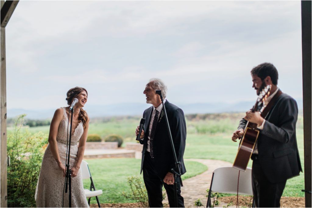 Musicians performing at outdoor wedding venue with scenic countryside views.