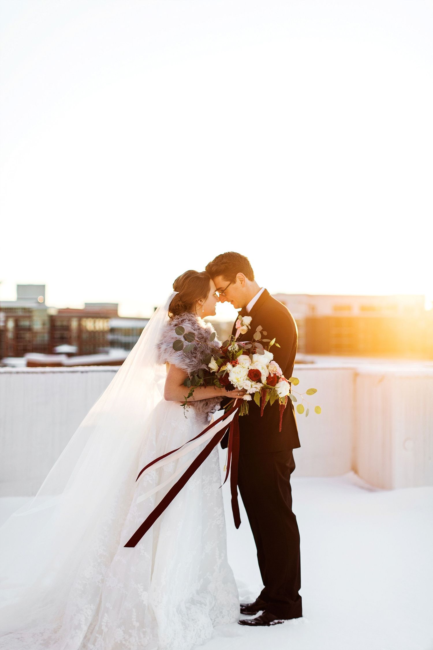 Bride and groom wedding portraits on a snowy rooftop at sunset