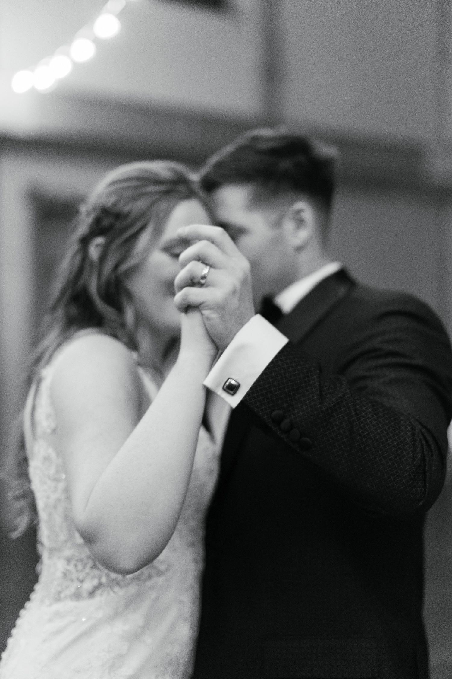 A black and white romantic first kiss photograph of a newlywed couple at their wedding ceremony.