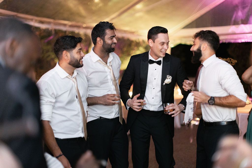 A group of wedding guests laughing and socializing during the reception party.