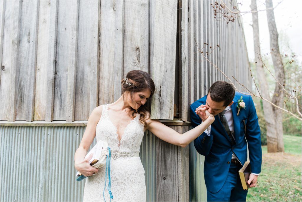 Couple in wedding attire sharing a playful moment against a rustic metal wall.