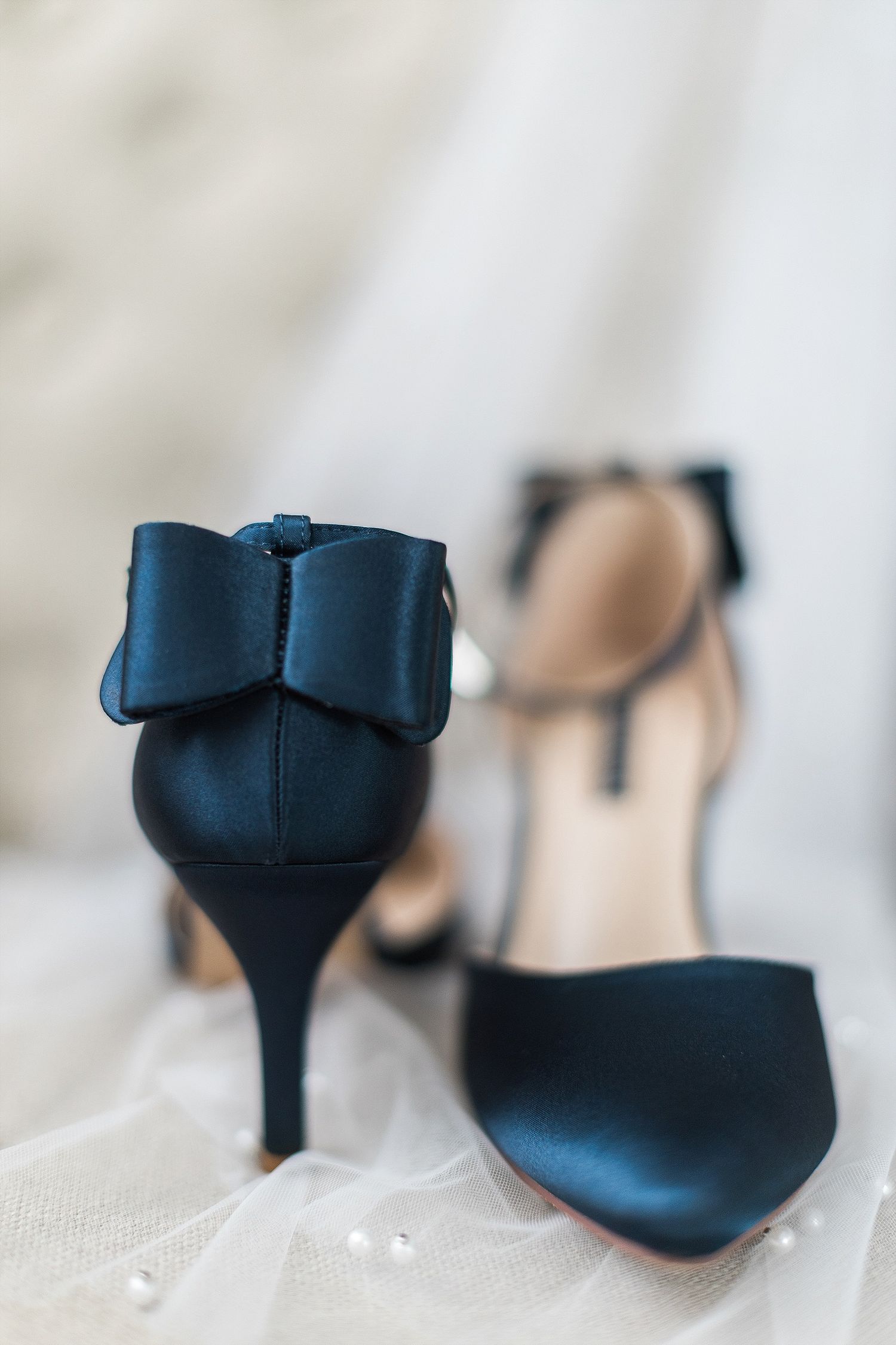 Navy blue wedding shoes with bow detail photographed on white tulle.