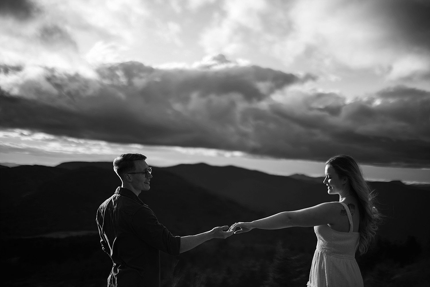 Epic black and white engagement photo with mountain views and dramatic clouds