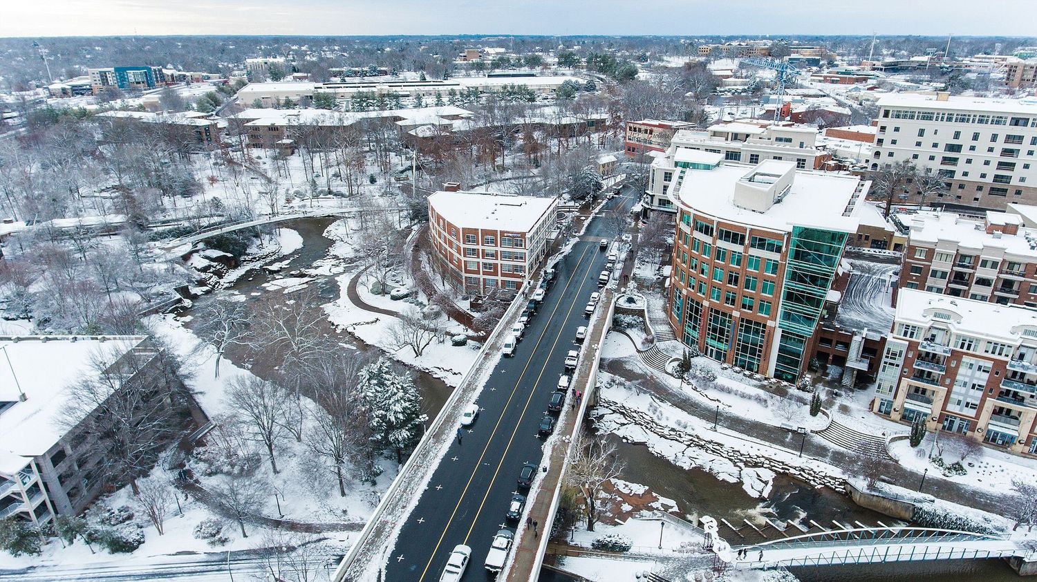 Snowy cityscape with modern buildings and streets viewed from above.