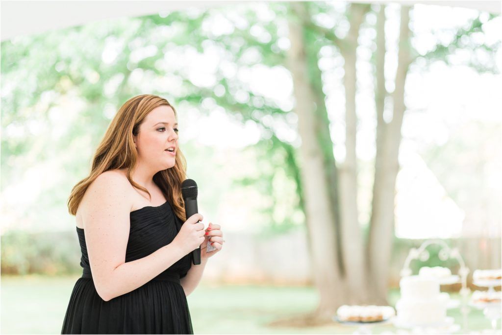 A guest in a black dress enjoying a moment at an outdoor wedding reception.
