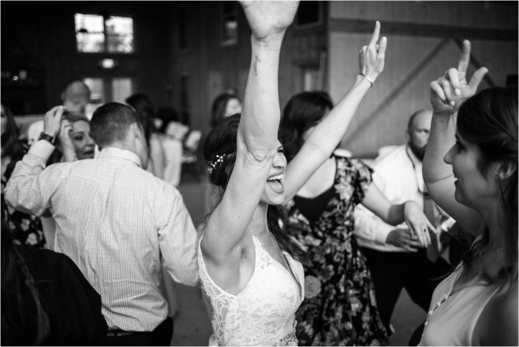 Wedding guests dancing with raised arms during a lively reception celebration.