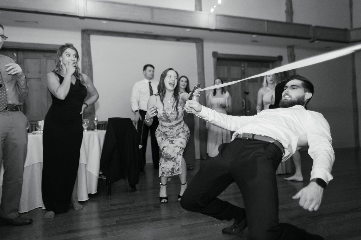 Black and white photo of people dancing and having fun at what appears to be a wedding reception or party.