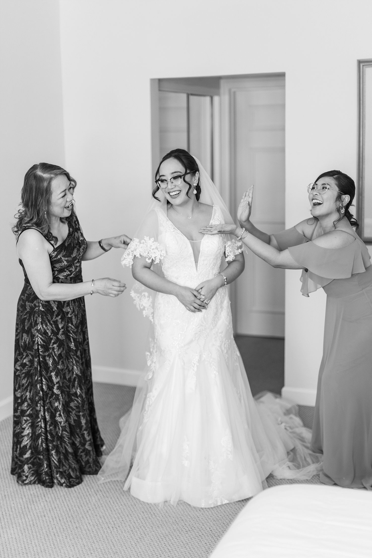 Three women share an excited moment during wedding preparations.