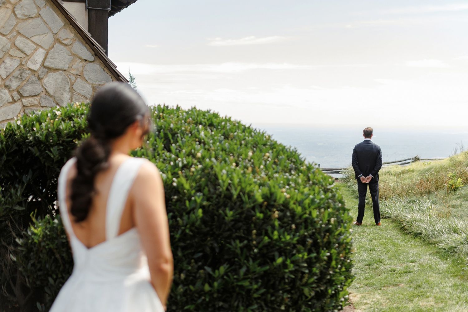 A couple shares an intimate first look moment on a scenic hilltop with ocean views.