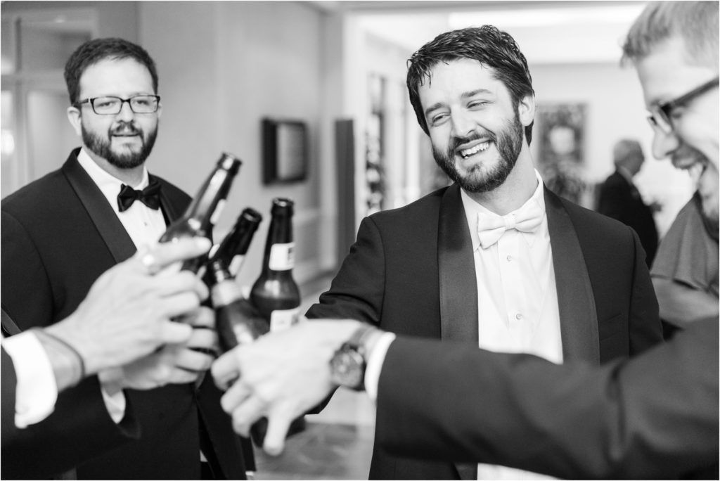 Wedding party members sharing drinks and laughter during pre-ceremony celebrations.