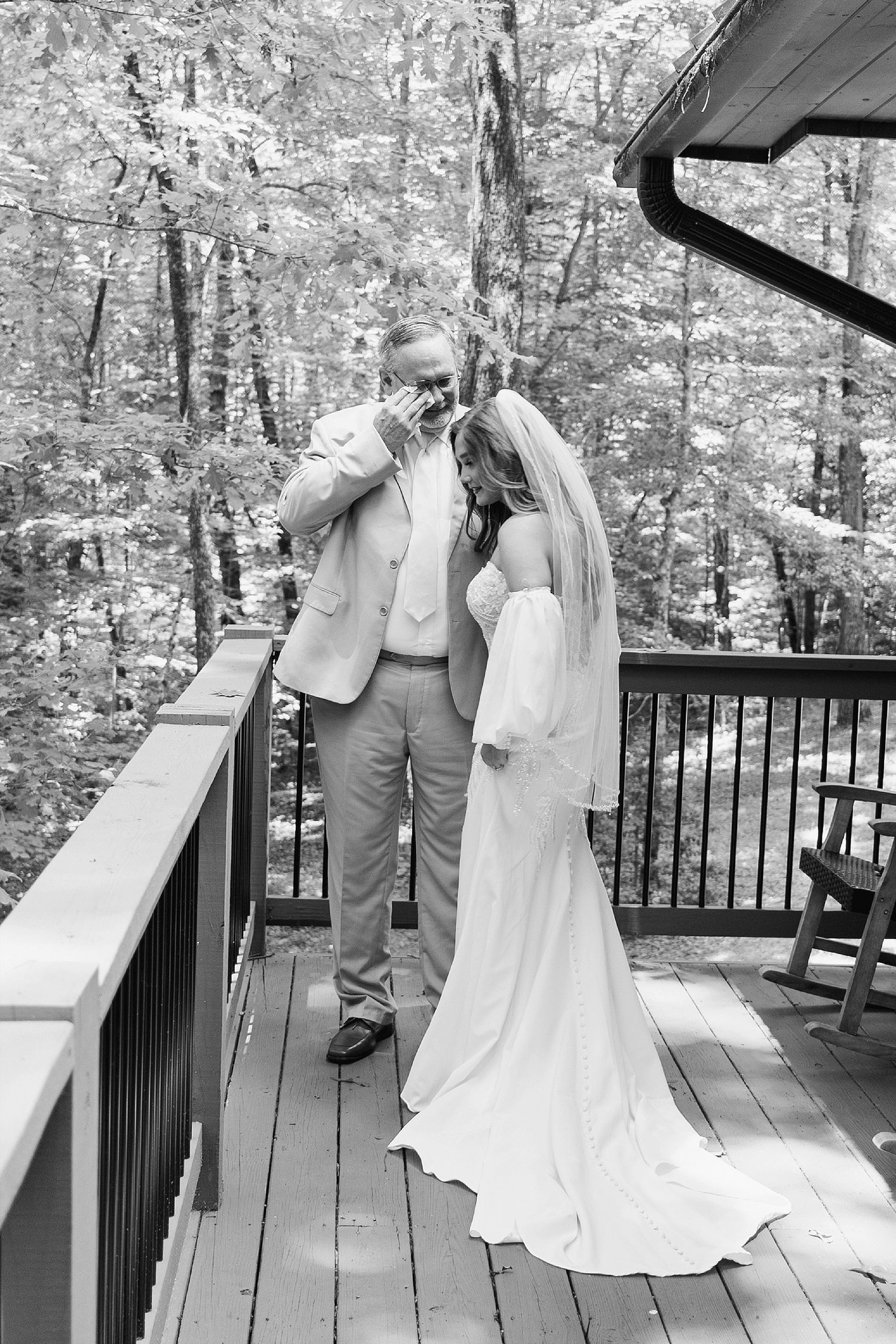 Black and white photo of an emotional moment on a wooden deck during a wedding ceremony.