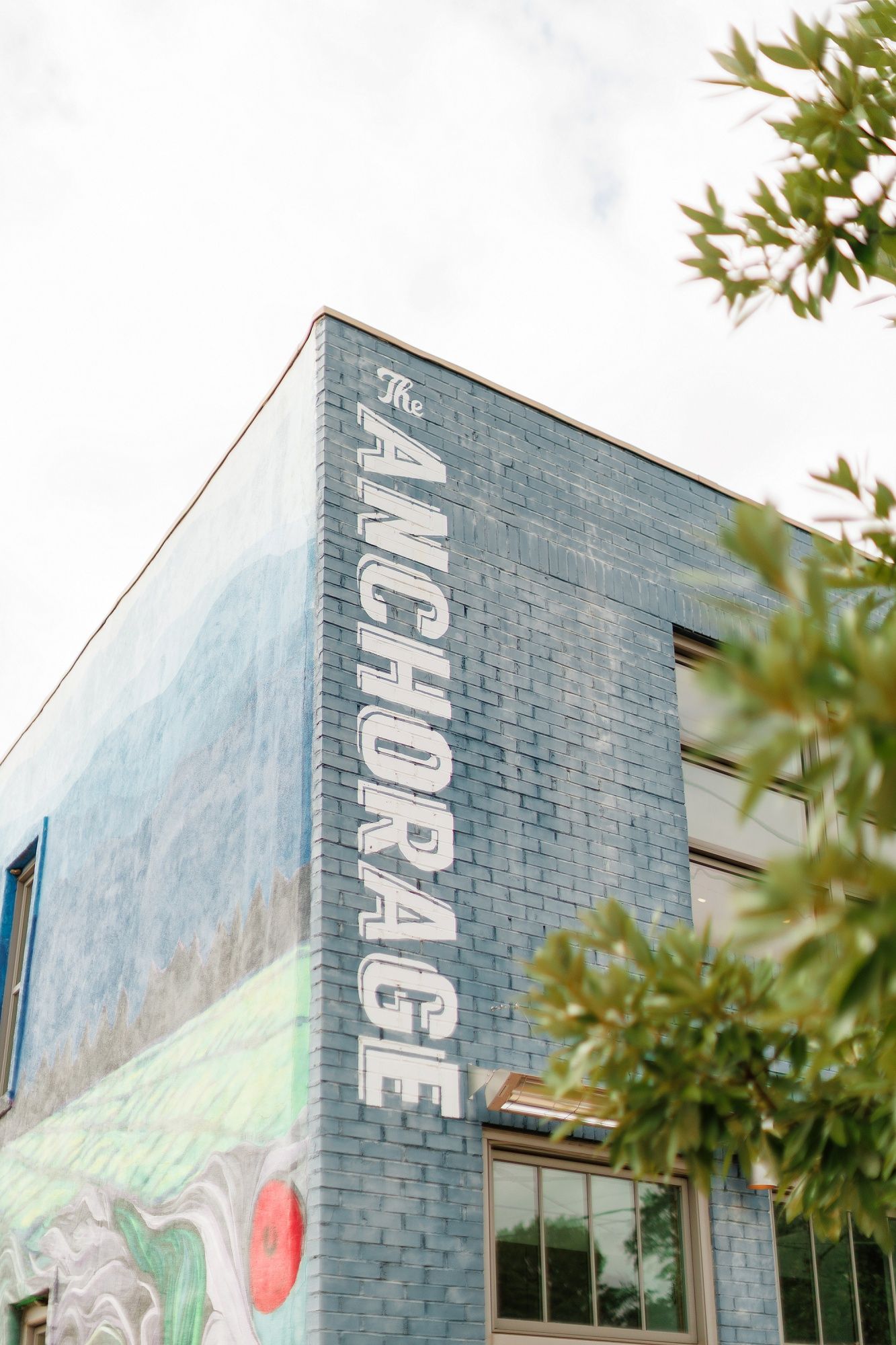 Exterior wall of a modern building with gray brick facade and partial view of a mural artwork.