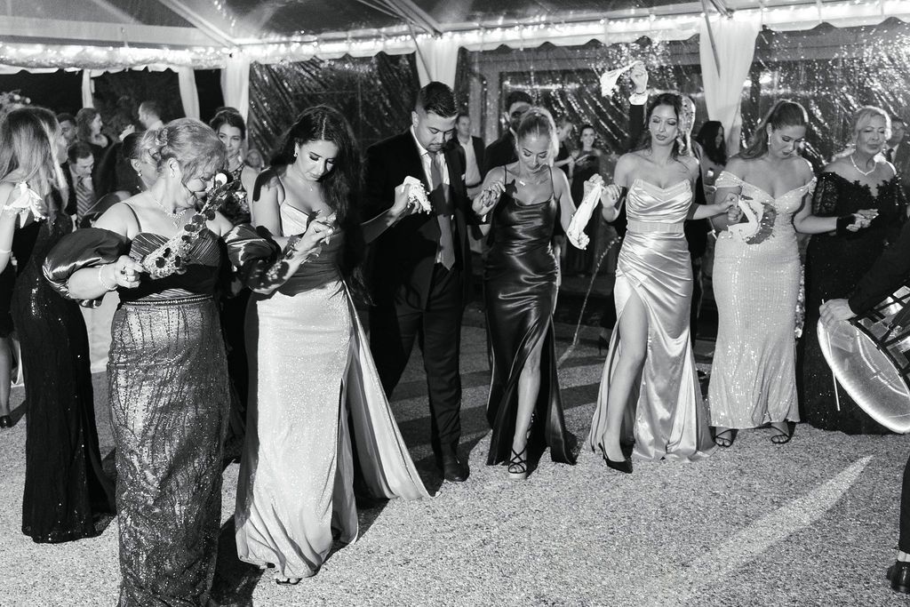 Vintage black and white photo showing elegant partygoers in formal evening attire at a glamorous social gathering.