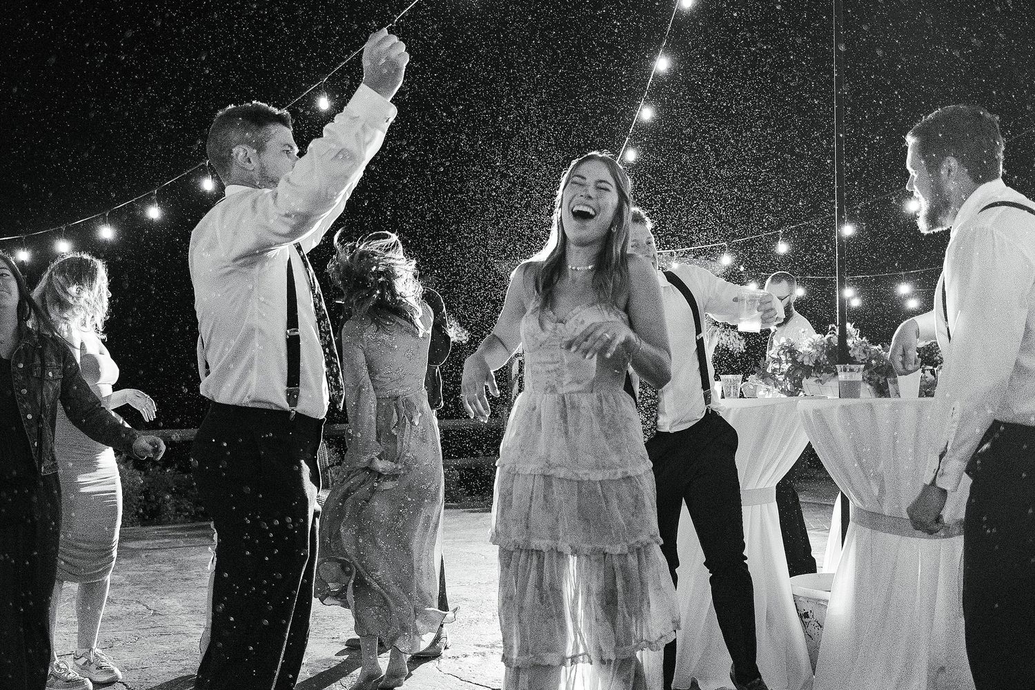 Wedding guests dancing and celebrating at a nighttime outdoor reception.