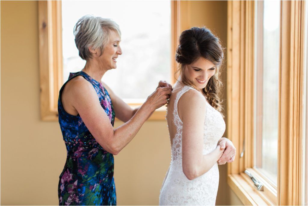 Intimate getting ready moment by window during wedding preparations.
