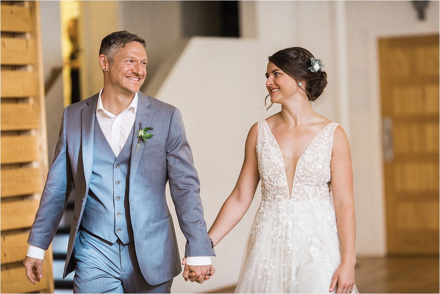 A couple shares a joyful moment in formal wedding attire in a bright indoor setting.