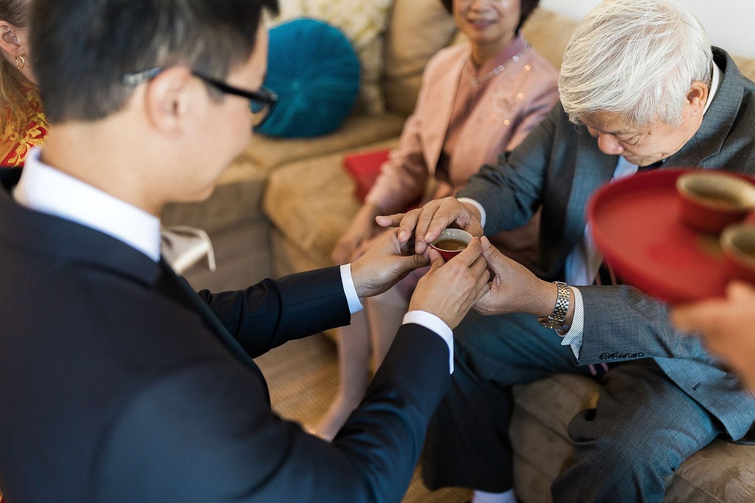Healthcare professional examines patient's hand while sitting on sofa during medical consultation.
