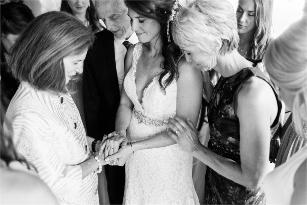 Emotional black and white moment of guests sharing a tender moment with the bride at a wedding reception.