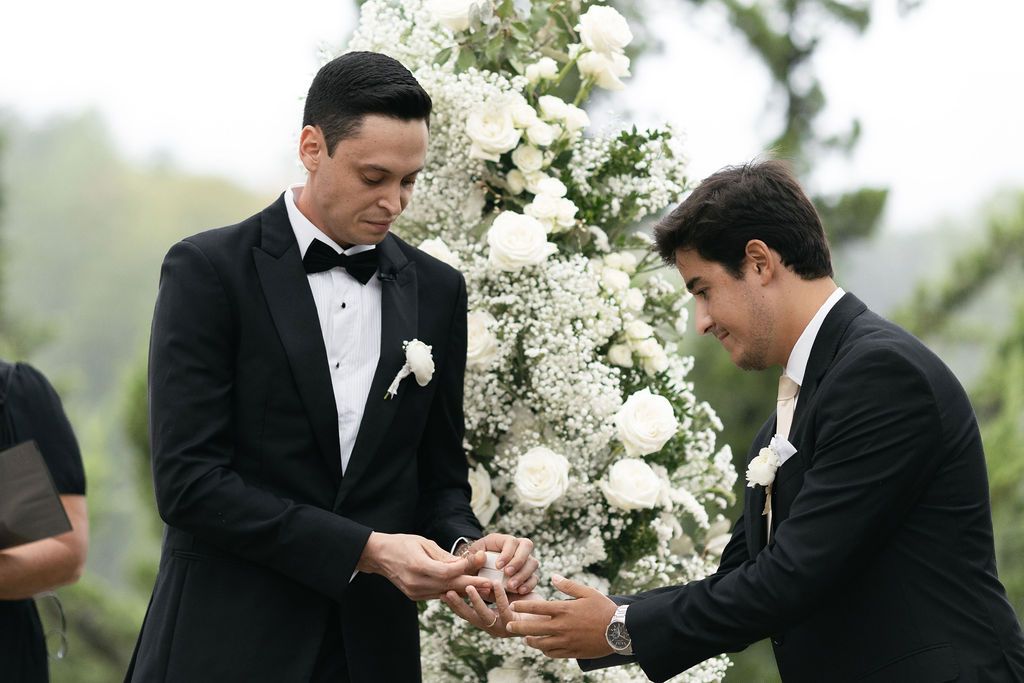 Wedding ceremony moment with white floral arrangements in outdoor setting.