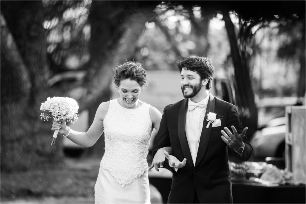 A joyful wedding moment captured in black and white on a sunny outdoor day.