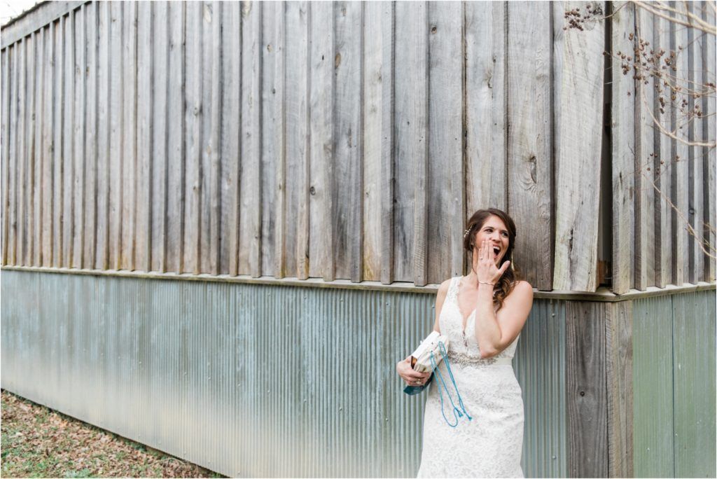 Bride in lace gown poses emotionally against weathered metal wall.