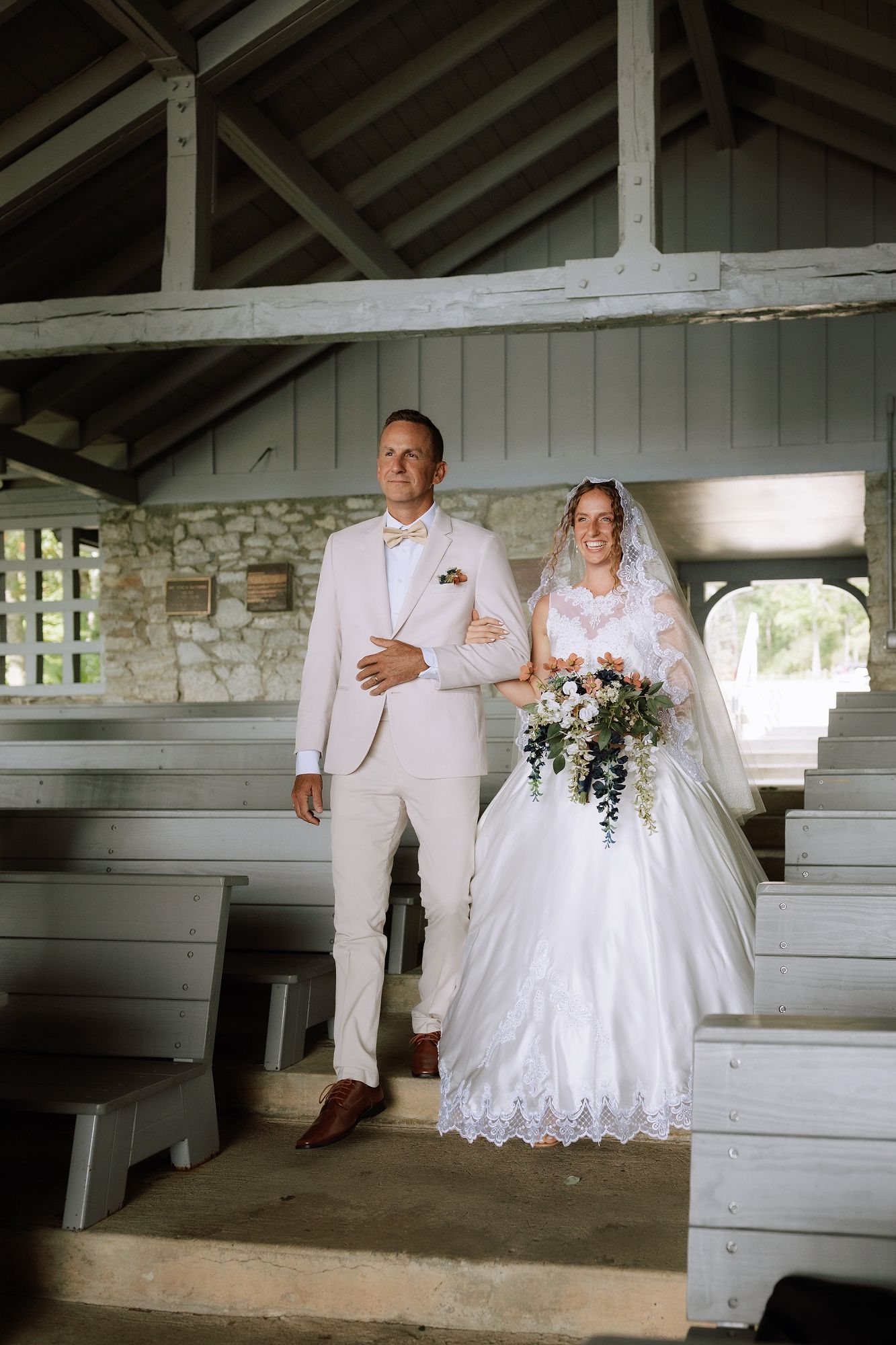 Bride and groom walking down the aisle in a rustic white chapel during their wedding ceremony.