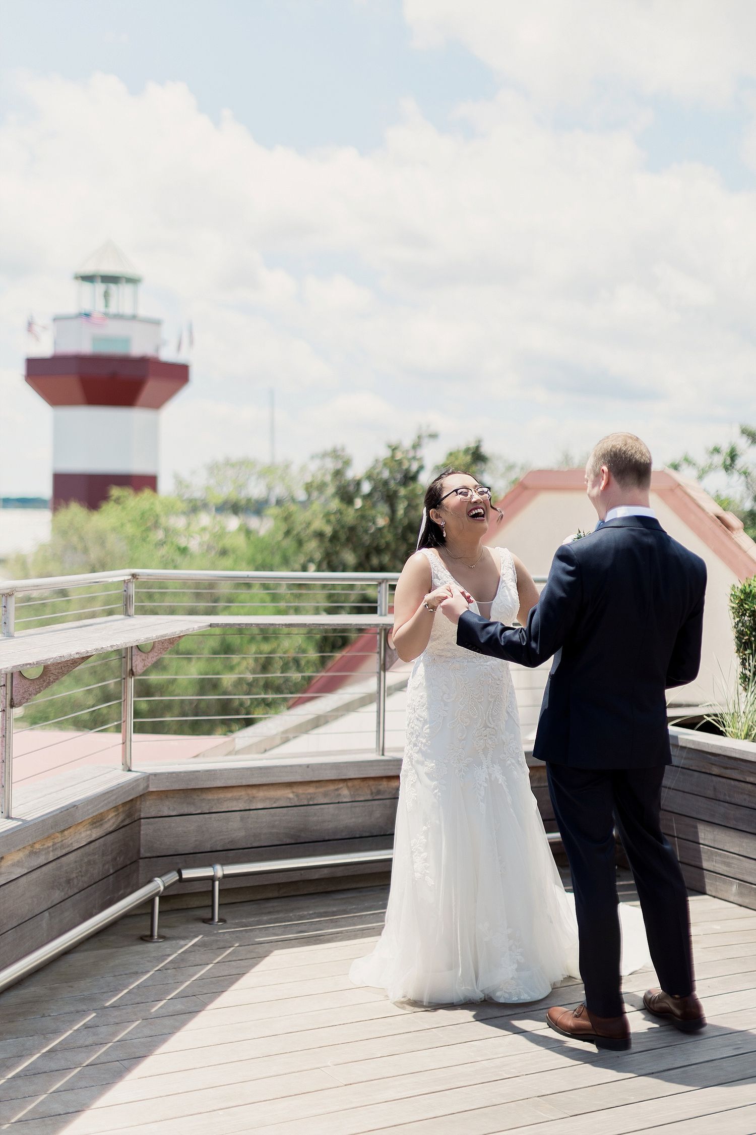 A couple dances on a deck with a red and white lighthouse in the background.