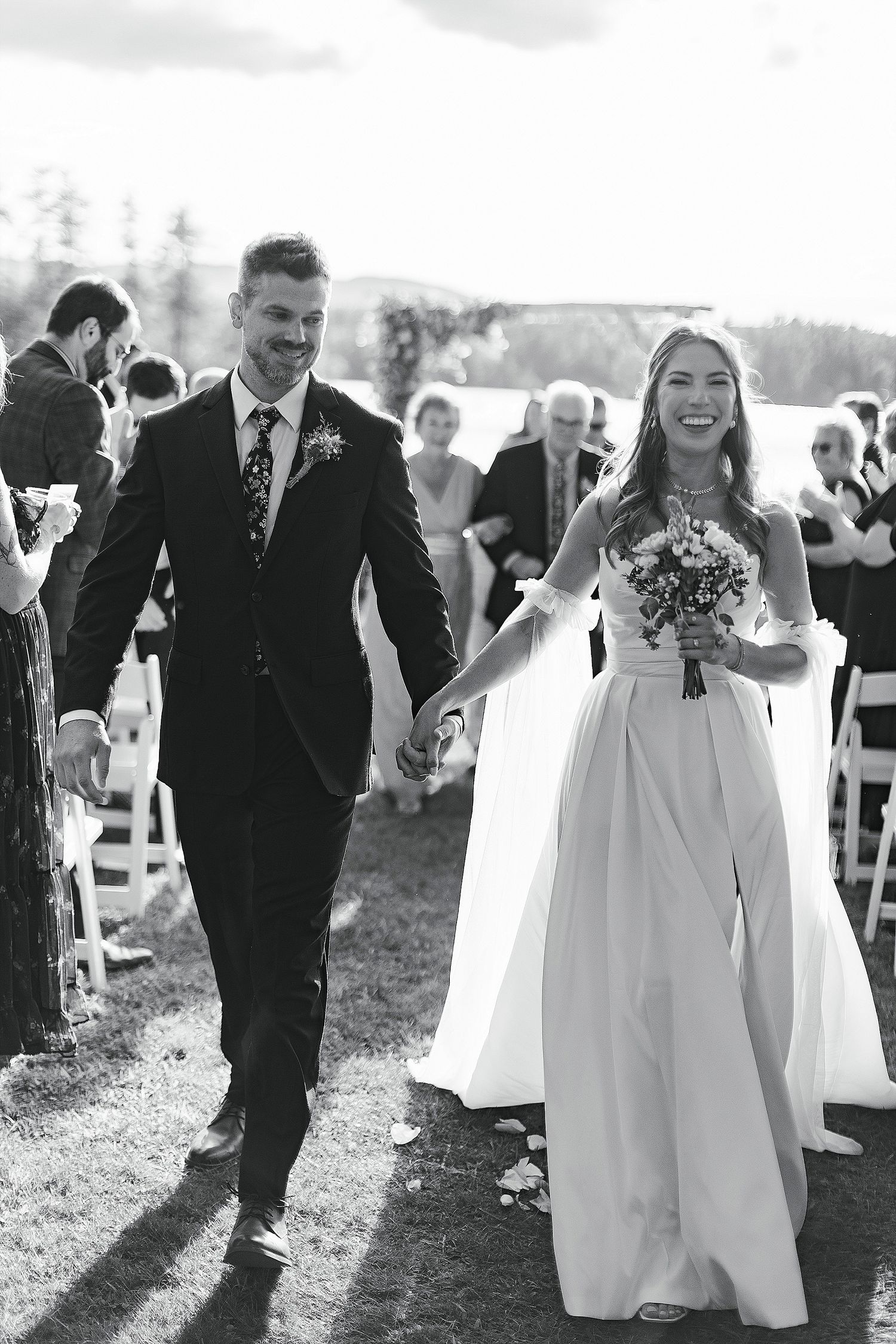 A wedding couple joyfully walks down the aisle after their outdoor ceremony.
