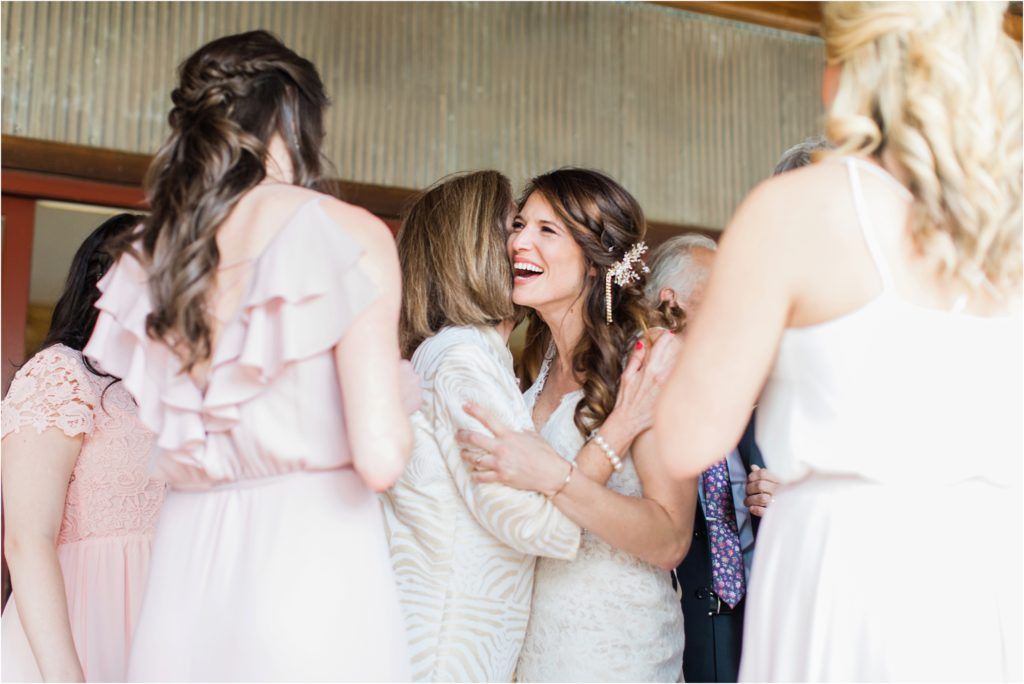 Bridesmaids in light pink dresses gather around the bride during wedding preparations.