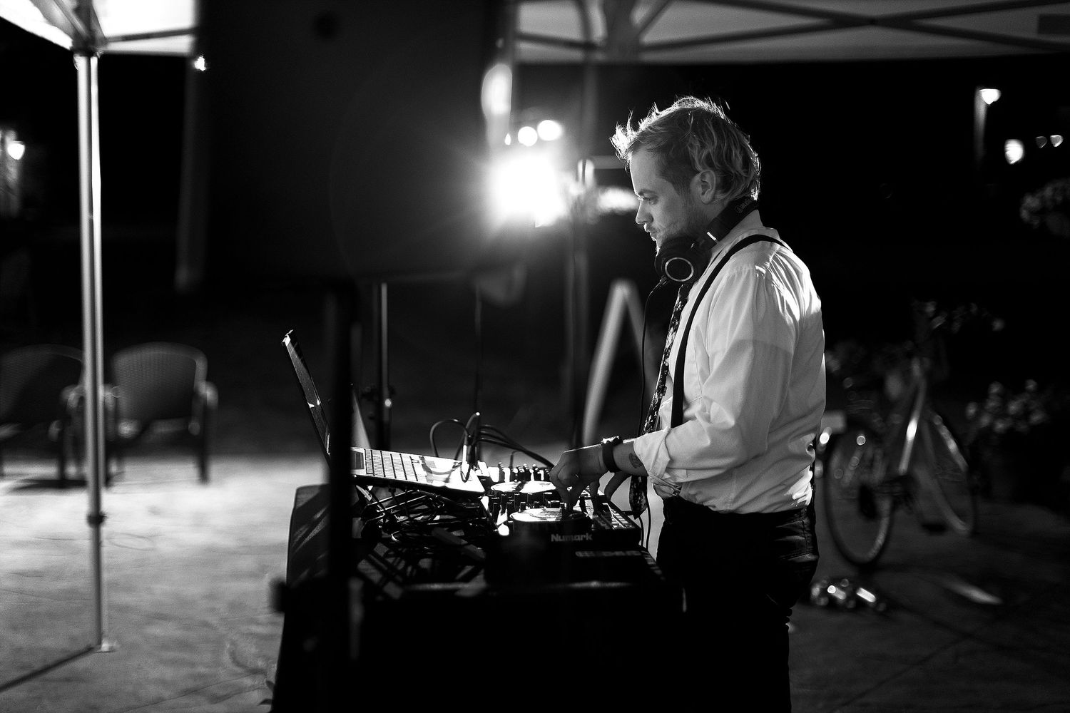 A DJ works at their equipment station during a nighttime outdoor event.