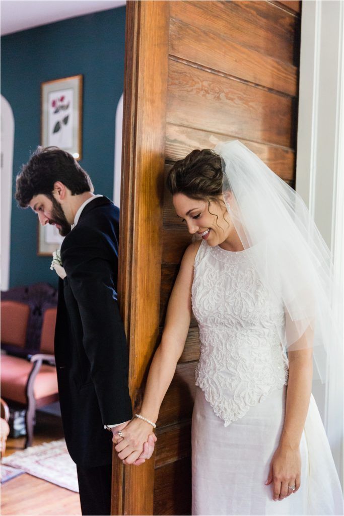 Couple holding hands around corner in intimate first look moment.