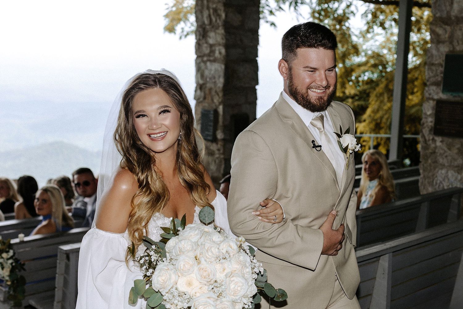 Newlyweds walking arm in arm at mountain venue with scenic views.