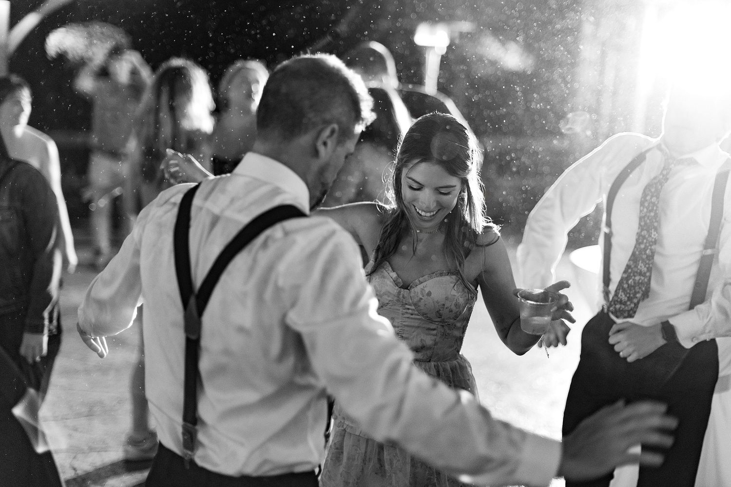 Wedding guests dancing and celebrating at a nighttime outdoor reception.