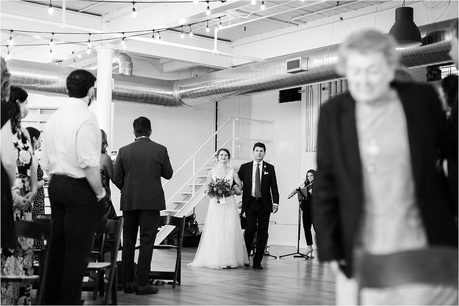 Black and white photo of a wedding reception with guests watching the couple enter.