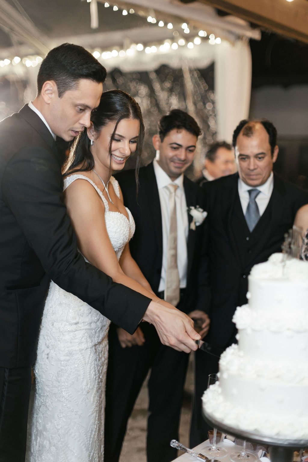 Newlyweds cutting their elegant white wedding cake together during reception.