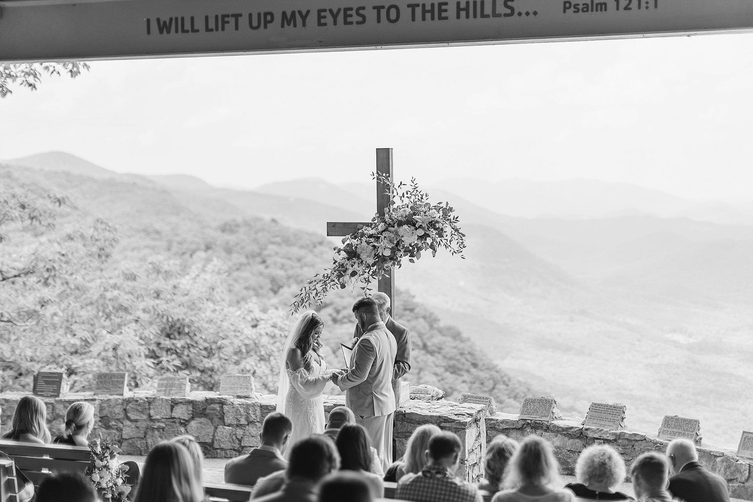 Black and white photo of mountain wedding ceremony with Bible verse and cross.