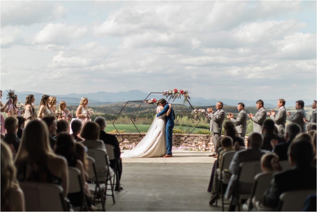 Wedding ceremony overlooking mountain views with guests seated on white chairs.