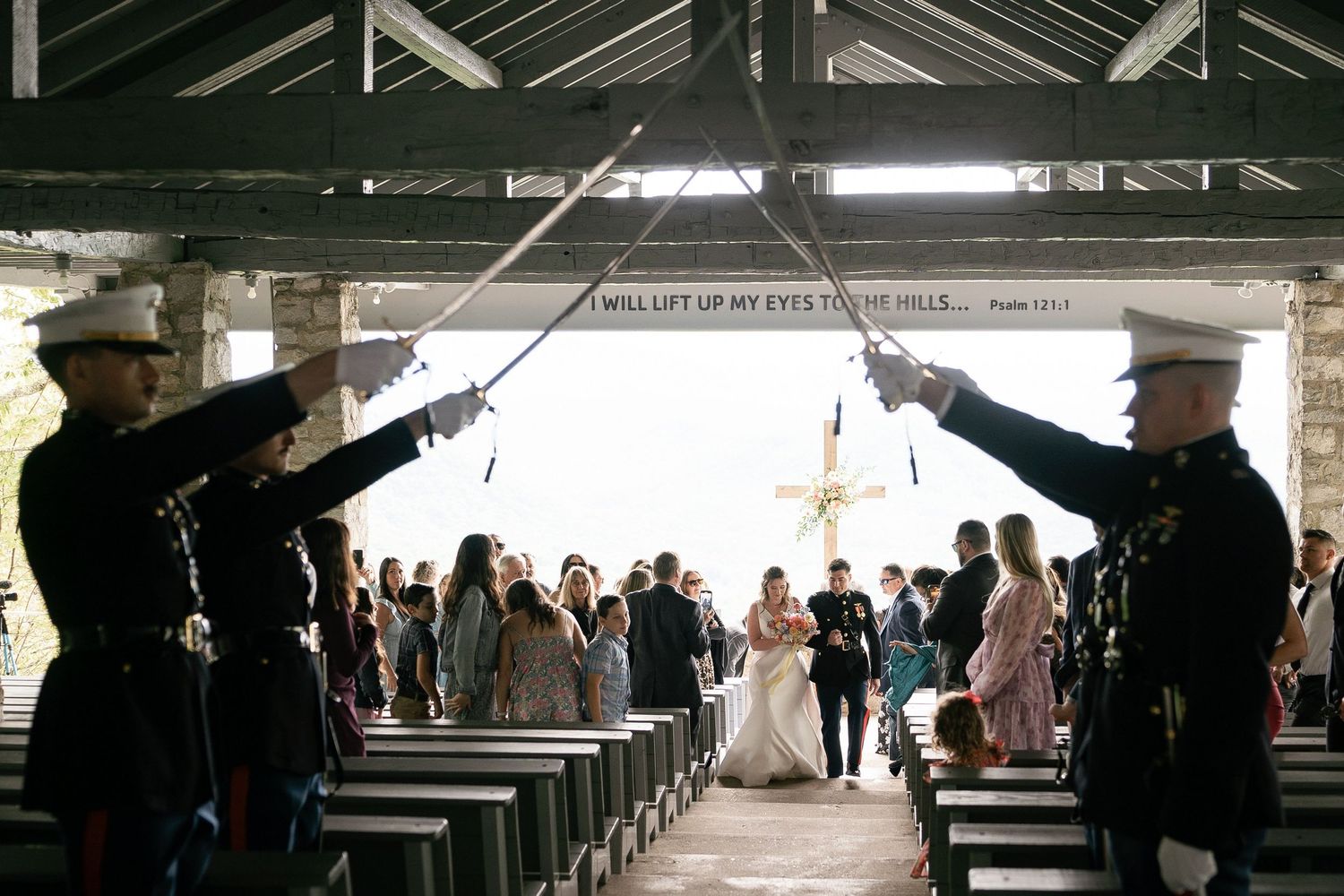Military officers with swords raised form an honor guard arch as wedding party exits church ceremony.