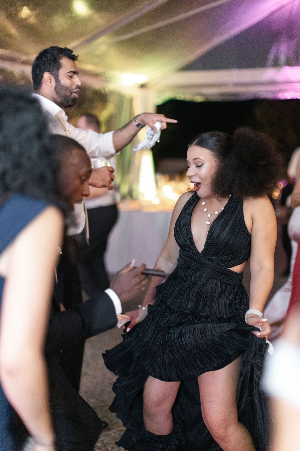 Party guests dancing energetically at a formal evening celebration with atmospheric lighting.