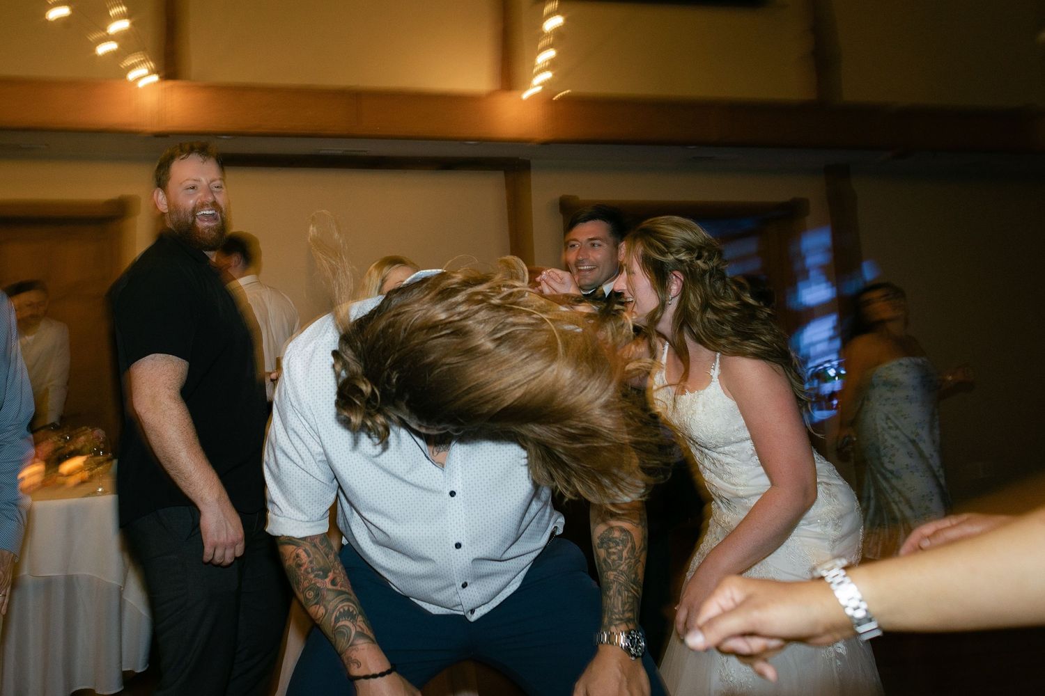 Wedding guests dance energetically on the dance floor during reception celebration as hair flies through the air.