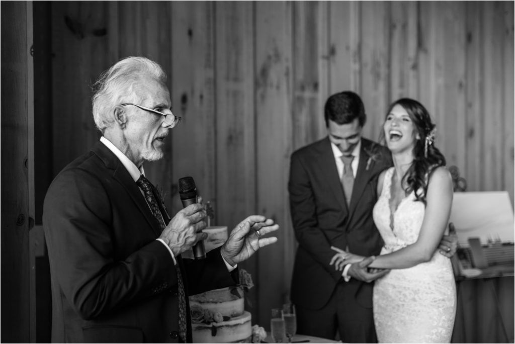 Black and white candid moment during wedding reception in rustic barn venue.