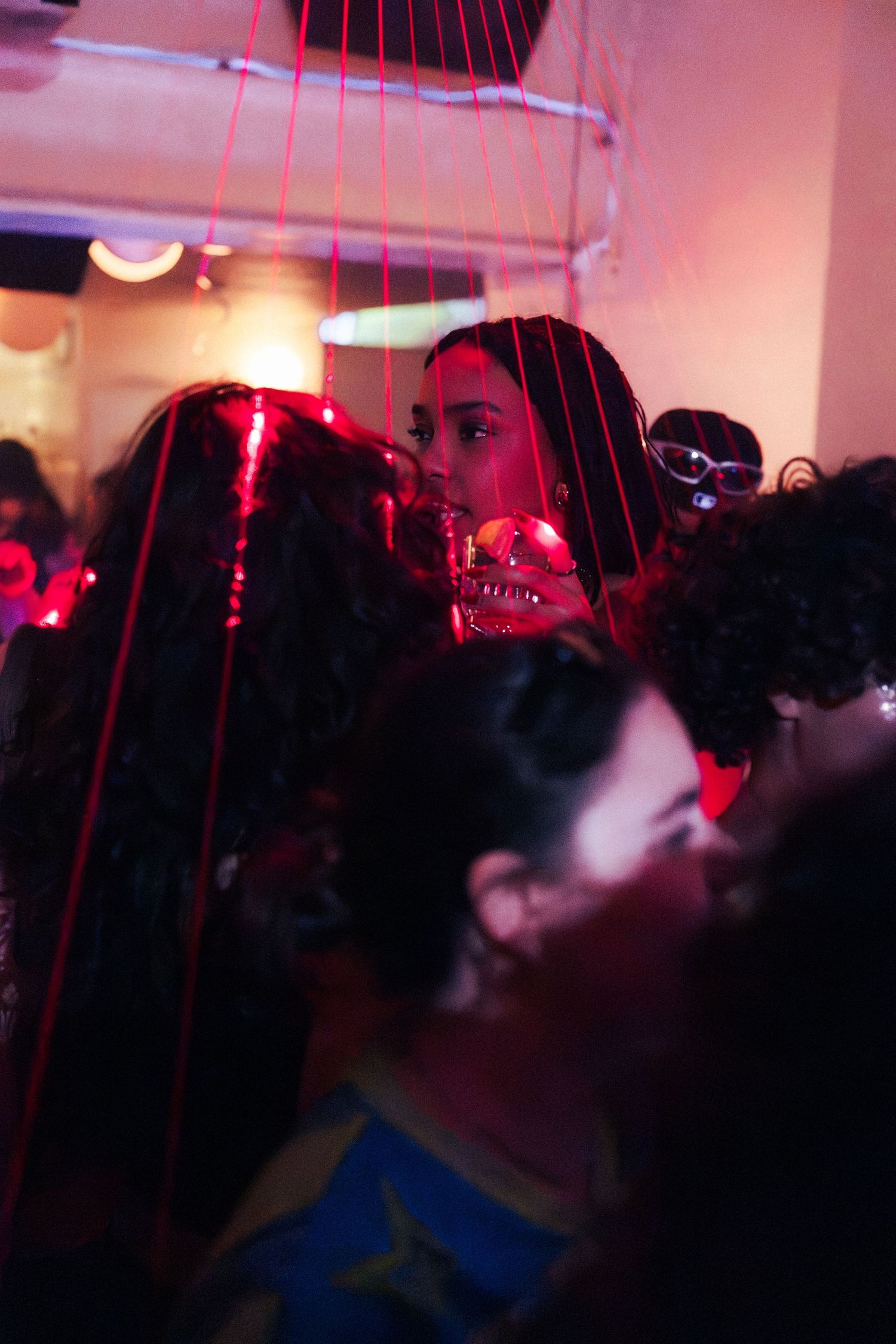 A crowd of people dancing under red laser lights at a vibrant nightclub party.