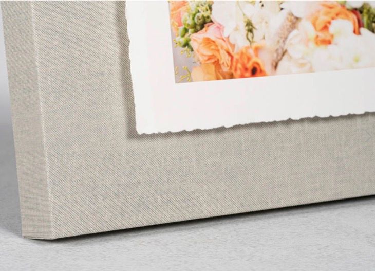 Detail of a linen photo album corner with a fine art floral wedding print and deckled edge mat.