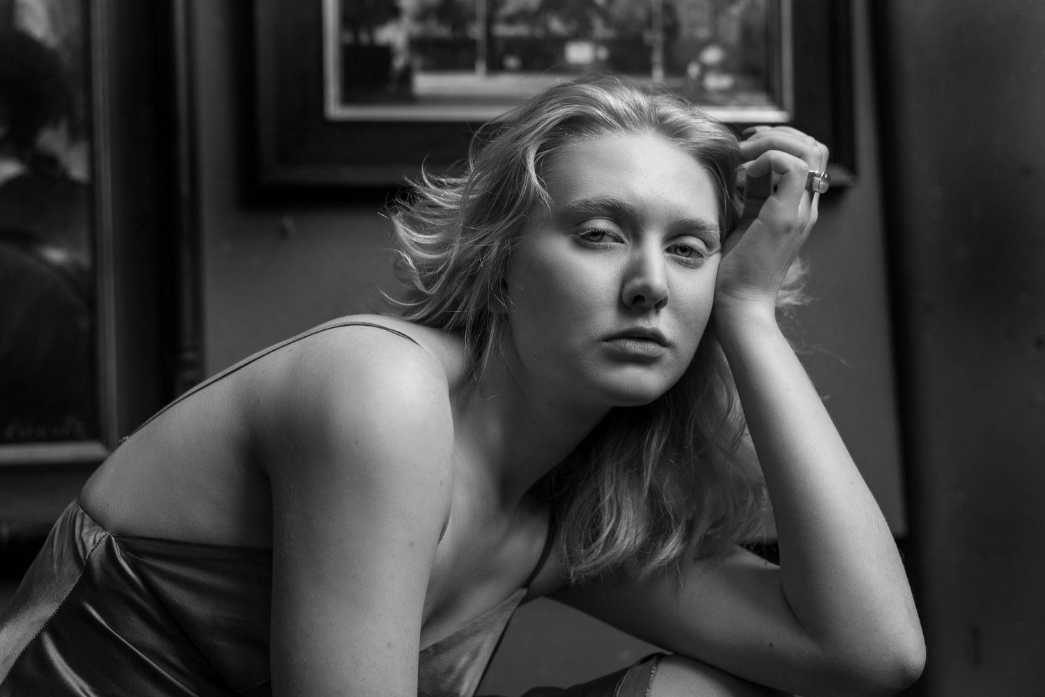 Black and white portrait of a young blonde woman leaning on her hand with a contemplative expression.