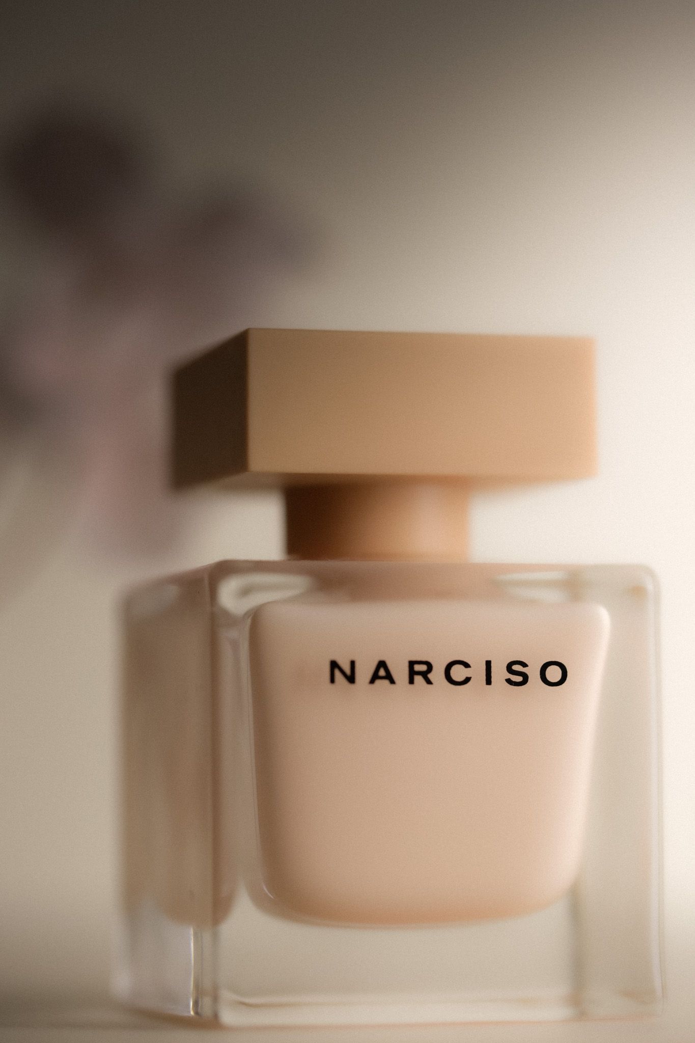 Narciso Rodriguez Narciso perfume bottle in nude pink glass with square cap on soft background.